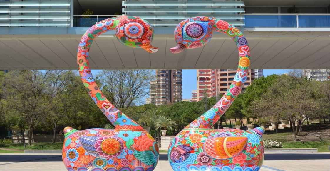 Figuras de dos cisnes de colores en un parque